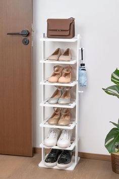 a white shoe rack with several pairs of shoes on it next to a door and potted plant