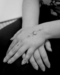 a woman's hand with a small tattoo on her left wrist and the moon in the middle