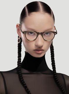 a woman with long braids wearing glasses and a black top is looking at the camera