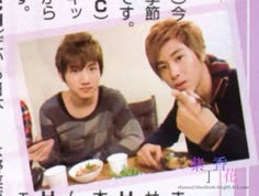 two young men sitting at a table eating food