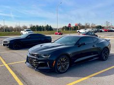 two chevrolet camaros are parked in a parking lot with other cars behind them