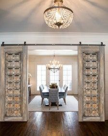 an open door leading to a formal dining room with chandelier and wooden floors