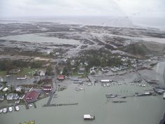 an aerial view of a flooded area with houses and boats in the water, surrounded by land