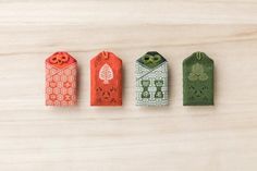 four small tags are lined up on a wooden surface, each with an orange and green design