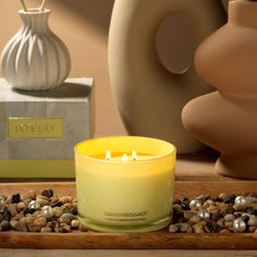 a yellow candle sitting on top of a wooden table next to a vase and other items