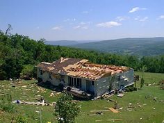 an old run down house in the middle of a field with lots of debris around it