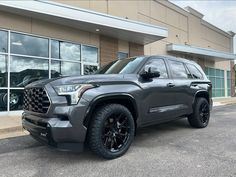 a gray truck is parked in front of a building with large windows and black rims