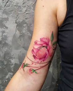 a woman's arm with a pink flower tattoo on it