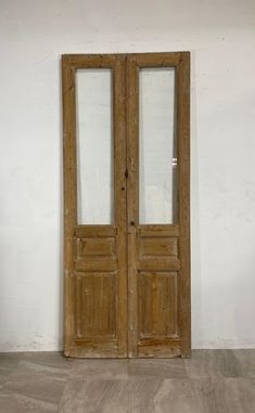 an old pair of wooden doors sitting on top of a hard wood floor next to a white wall