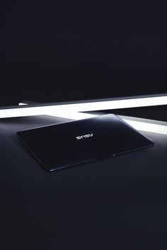 a laptop computer sitting on top of a black table next to a white light strip