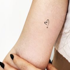 a woman's arm with a small heart tattoo on the left side of her arm