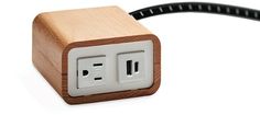 an electrical outlet plugged into a wooden box with two black wires attached to it