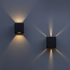 two square lights are on the wall next to each other, with one light shining down