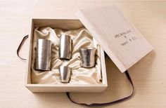 four silver cups in a box on a table