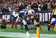 a football player jumping into the air to catch a ball in front of a crowd