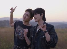 two young men standing next to each other in a field