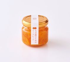 a jar of orange marmalade sits on a white surface with a tag in front of it