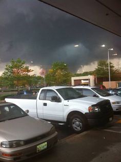 several cars parked in a parking lot under dark clouds