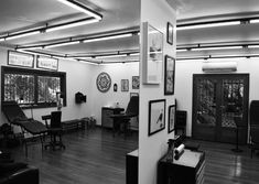 a black and white photo of a living room with pictures on the wall, couches and chairs