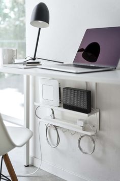 an open laptop computer sitting on top of a white desk next to a lamp and chair