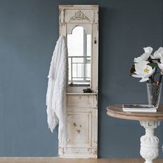 a room with blue walls, white furniture and flowers in a vase on the table