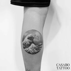 a black and white photo of a wave tattoo on the left calf sleeve by casao tattoo