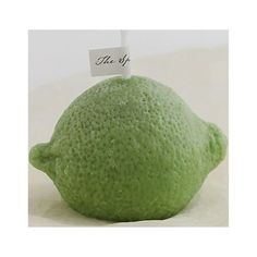 a green lemon with a tag on it's head sitting on a white surface