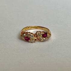 a yellow gold ring with three stones and two diamonds on the side, sitting on a white surface