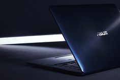 an open laptop computer sitting on top of a black table next to a white light