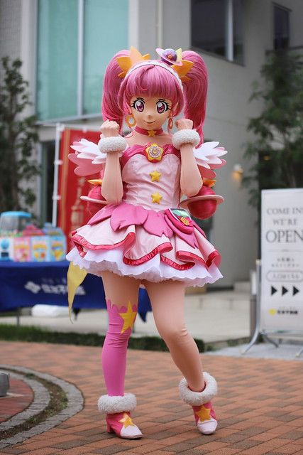 a very cute looking girl in a pink dress and some big pretty shoes with her hands on her head