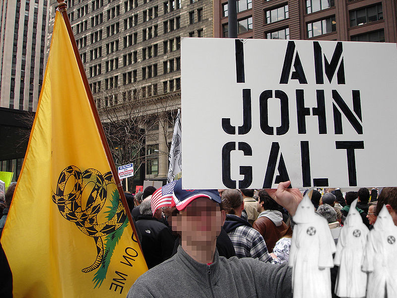 Protester seen at Chicago Tax Day Tea Party protest with sign reading 'I am John Galt'. Edited to protect protester's identity. Three tiny Klansman in hoods and robes have been superimposed in the corner of the picture.