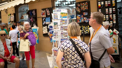 Tourists looking at postcards outside a souvenir shop in Malaga (Credit: Getty Images)