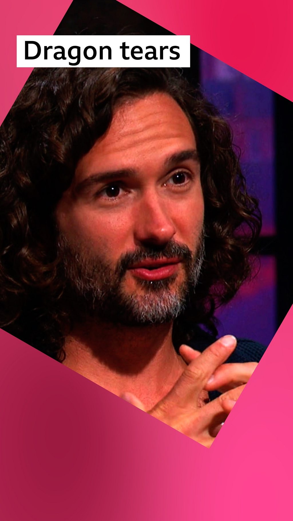 A man, Joe Wicks, with dark curly hair and beard holds his hands together