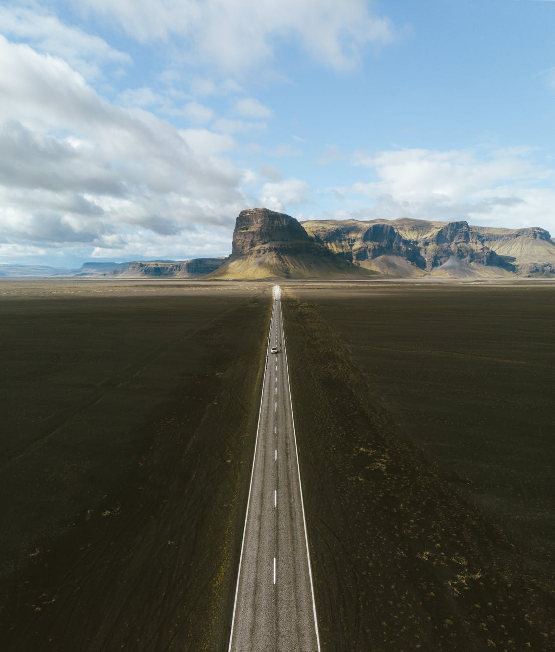 drone shot of a vehicle driving on long highway