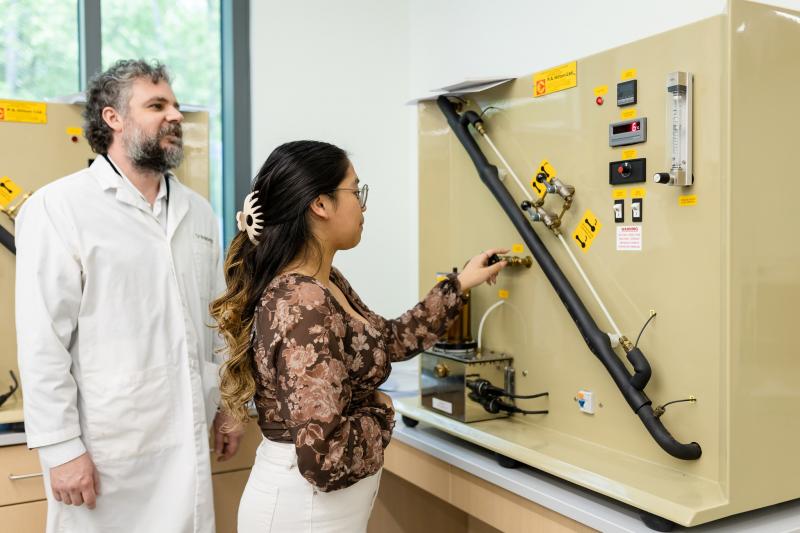 Teacher guides student working on piece of equipment