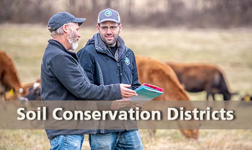 technical_assistance-farmer and conservation planner talking in pasture with cows behind them