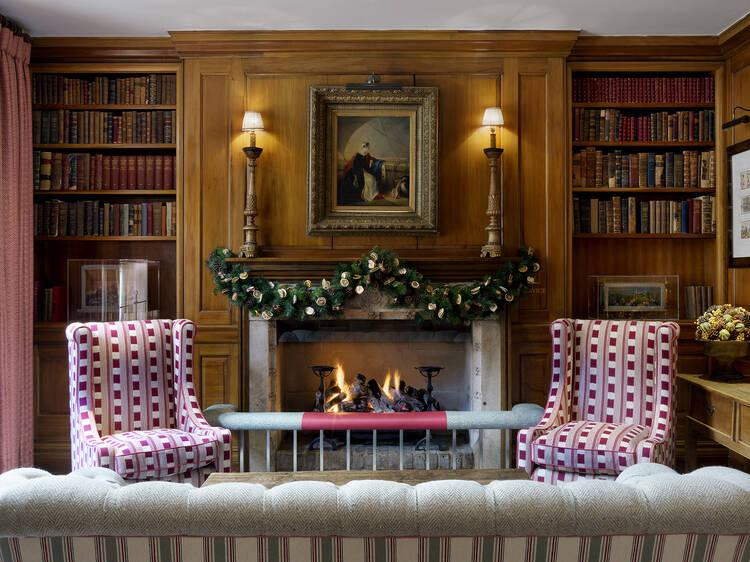 A cozy living room decorated for Christmas with an open fire at London's Covent Garden Hotel.