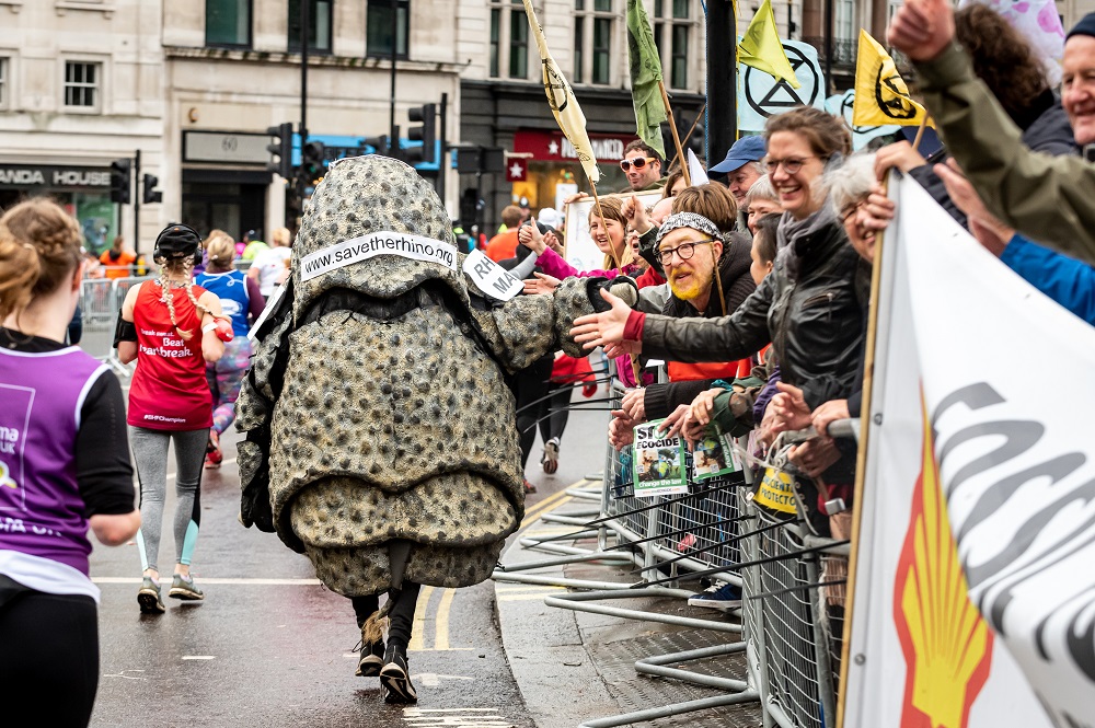 Rhino costume runner high fives spectators at the Royal Parks Half Marathon