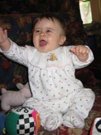 A picture of Carolyn sitting up and reaching upward, an enormous smile upon her face.