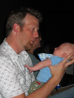 Jeff Veen holds Arlo in his hands as they give each other inquisitive looks.