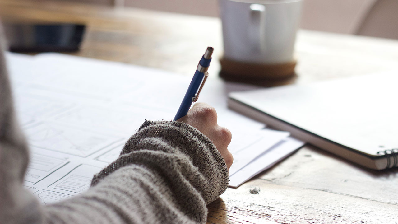 Hand holding pen writes on notepad