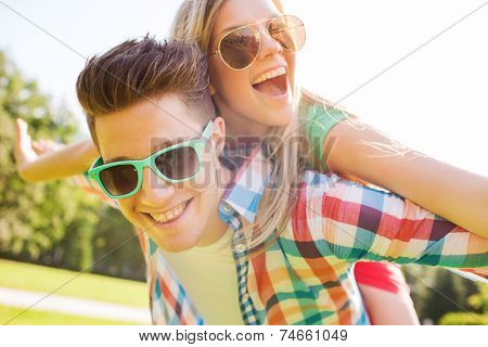 holidays, vacation, love and friendship concept - smiling teen couple in sunglasses having fun in summer park