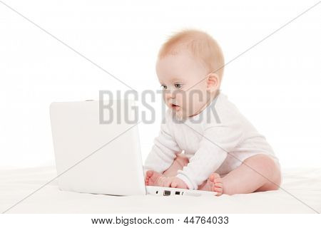 Cute baby with laptop on the white bed