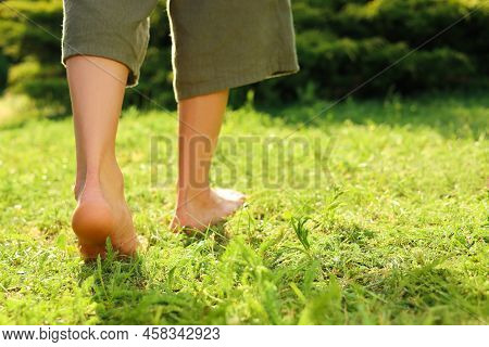 Woman Walking Barefoot On Green Grass Outdoors, Closeup. Space For Text