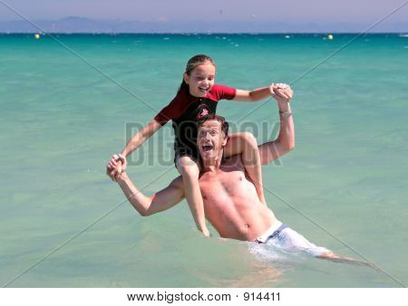 Young Father And Daughter Playing On Beach In Sea